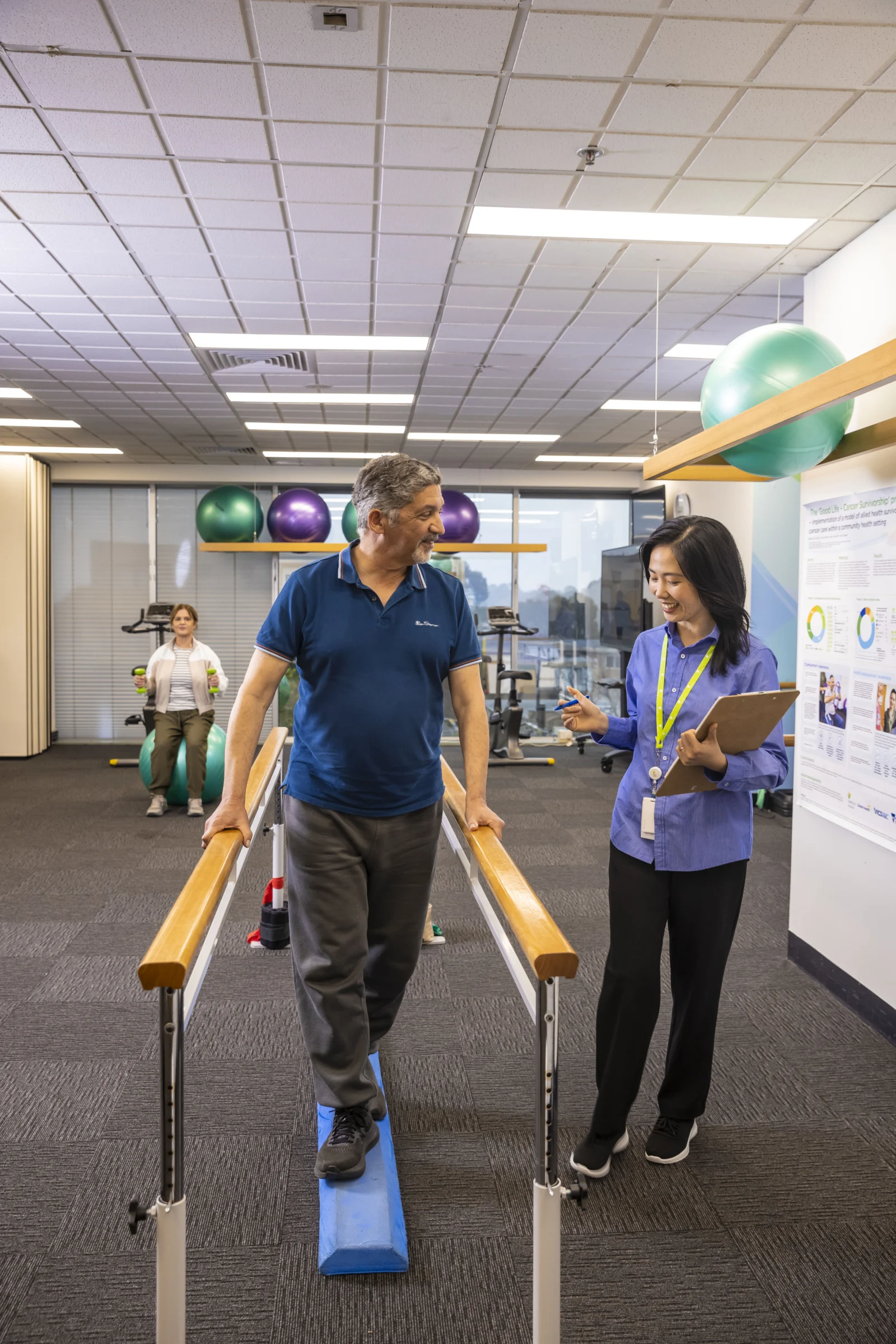An older man walking on a low beam while holding two bars to balance