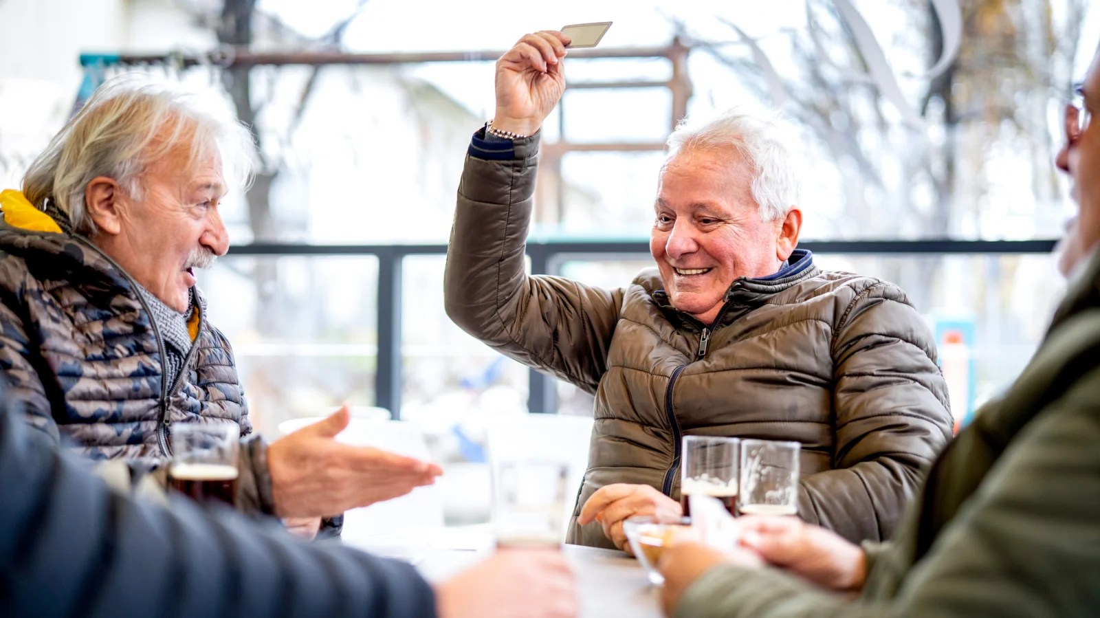 A group of older men chatting and playing cards