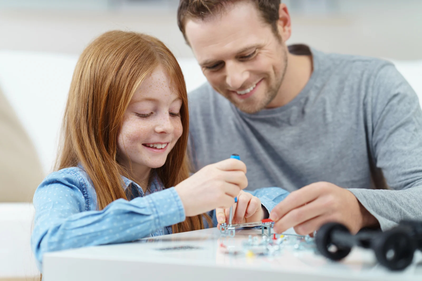 A father and daughter building a small toy together